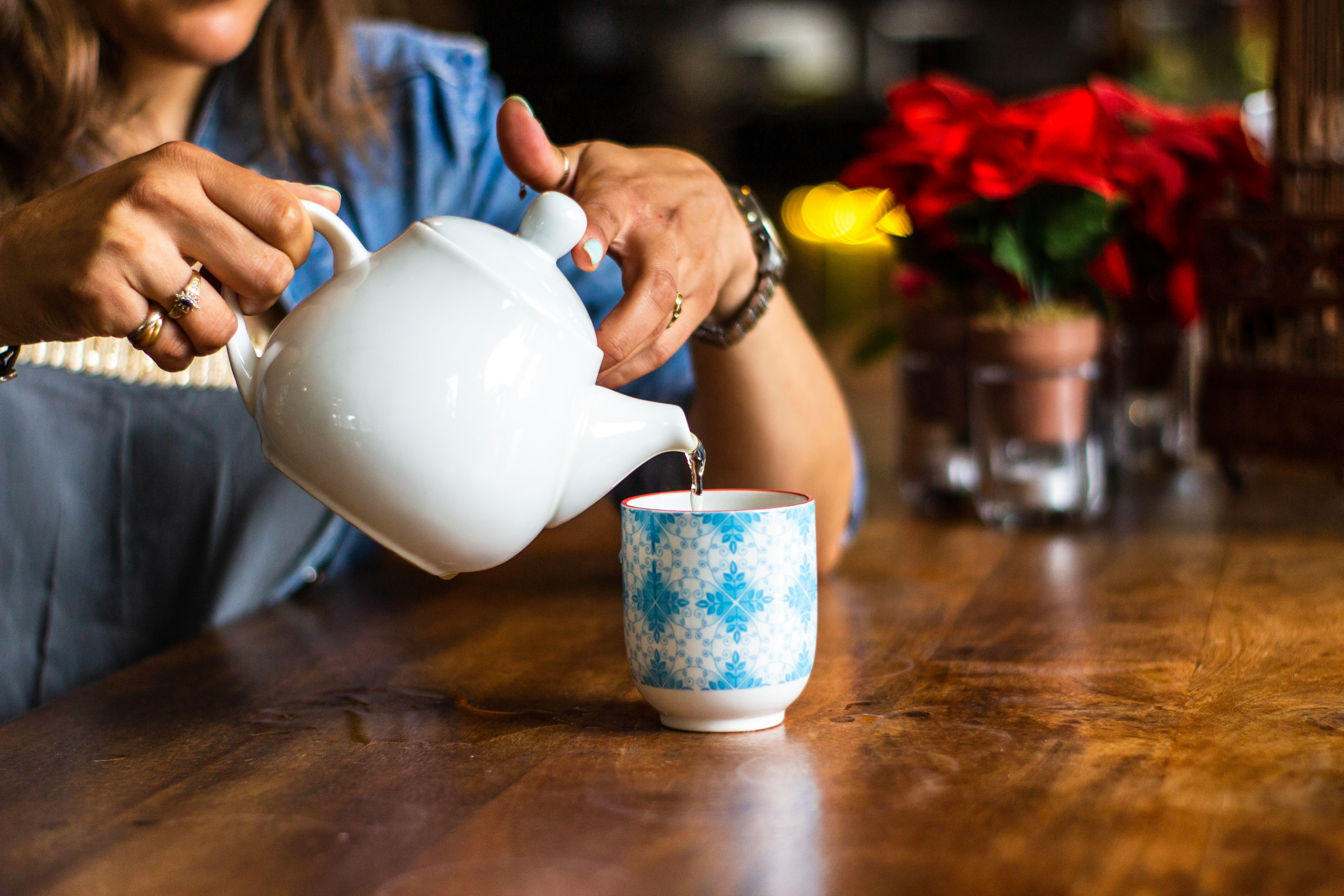 Une femme verse de la tisane dans une tasse, symbolisant un moment de détente et de bien-être.
